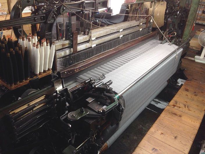 batak Clothはすべてこのショーンヘル式低速織機で織られています。ゆっくり織り上げ、タテ糸のストロークもたっぷりありますので、糸に膨らみと弾性がもたらされ、活き活きとした高級感のある服地が織り上がります。世界でもほとんど稼働していない旧式の織機です。